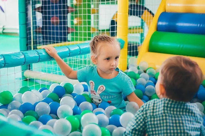 Дети в сухом бассейне с шарами играют.